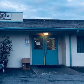 An evening view of a commercial building with teal doors and a welcoming entrance.