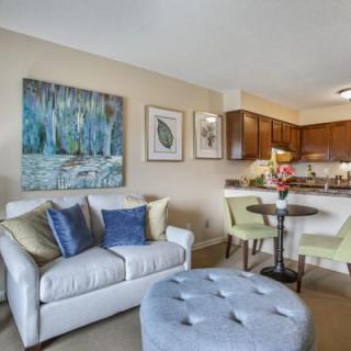 A cozy living room with a sofa, artwork, and an open kitchen area.