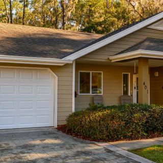 A cozy residential house with a garage and driveway surrounded by trees.