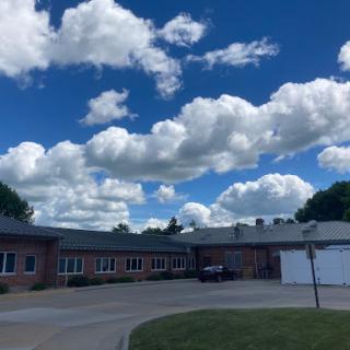 A picturesque view of a building under a bright blue sky adorned with fluffy clouds.