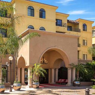 A Mediterranean-style hotel exterior with palm trees.