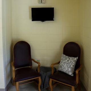 A cozy waiting area featuring two wooden chairs and a wall-mounted TV.