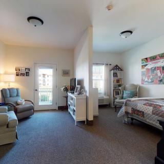 A cozy apartment interior featuring a bedroom and living area, with comfortable furniture and warm decor.