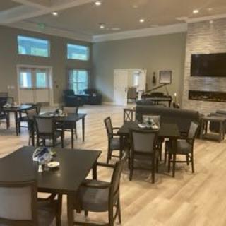 A modern dining area with tables and chairs on a wood floor.