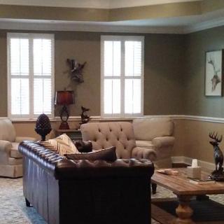 A spacious living room with elegant furniture, including a leather sofa and armchairs, decorated with artwork and sculptures.
