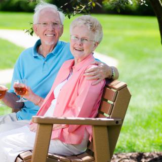 An elderly couple enjoying a sunny day in the park, sitting together on a bench.