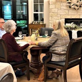 A group of people sharing a meal and conversation in a cozy dining room.