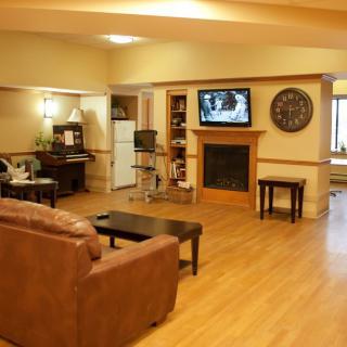 A cozy living room with a sofa, television, and fireplace on a wooden floor.