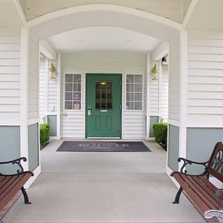 A welcoming porch with a green door, framed by two benches.