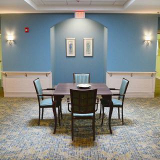 A cozy dining area with a table and four chairs against a blue wall.
