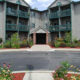 A residential apartment building with balconies and a landscaped entrance.