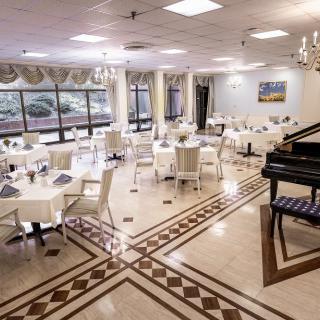 An elegant dining area with neatly arranged tables and a piano.