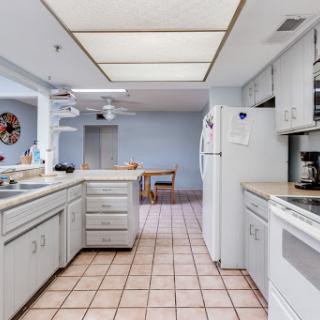 A spacious kitchen featuring white cabinetry and tiled flooring, designed for functionality and comfort.