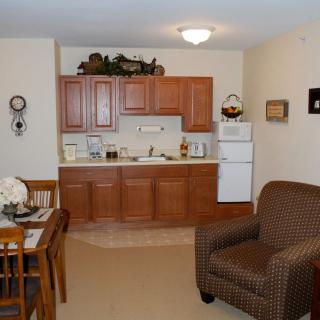 A cozy apartment interior featuring a small kitchen area with wooden cabinetry and a compact dining set.