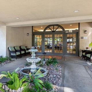 An inviting entrance with a fountain and cozy seating area surrounded by greenery.