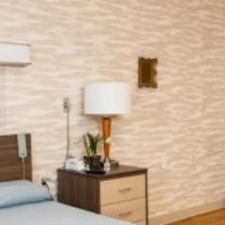 A neatly arranged bedroom with a bedside lamp and nightstand.