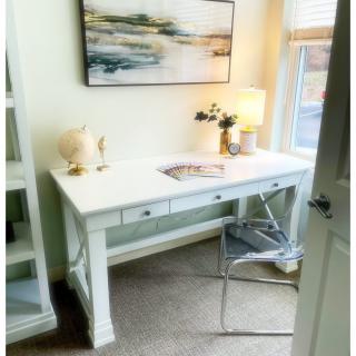 A bright and minimalist home office setup featuring a white desk, modern chair, and decorative elements.