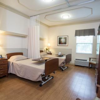 A clean and organized hospital room with two patient beds, separated by a curtain.