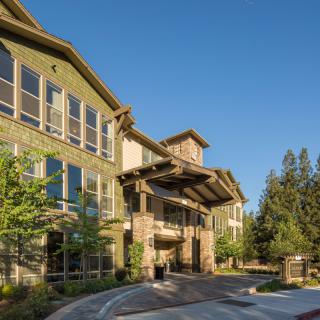 A modern residential building with a scenic exterior and trees surrounding the entrance.
