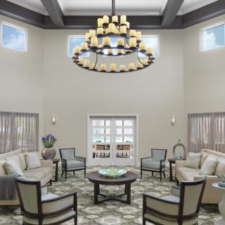 A spacious, elegantly designed living room featuring a grand chandelier and comfortable seating arrangement.