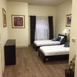 A cozy bedroom featuring twin beds, minimalist decor, and framed artwork on the walls.