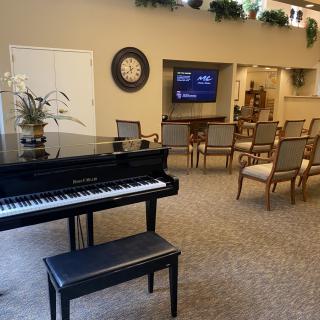A cozy room with a piano, seating area, and a TV on the wall.