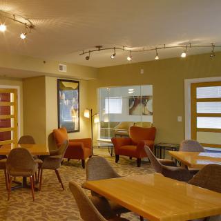 A modern lounge area with tables and chairs, featuring warm lighting and contemporary decor.