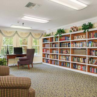 A cozy library corner with bookshelves, a computer desk, and comfortable seating.