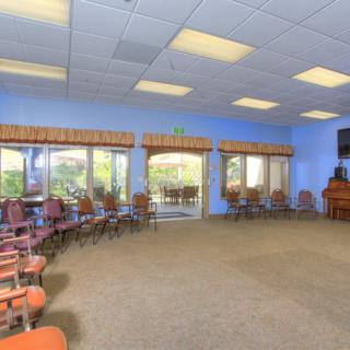 A spacious conference room with a circle of chairs, large windows, and ceiling lights.