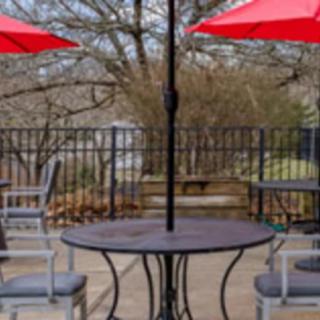 Outdoor patio with tables, chairs, and red umbrellas.