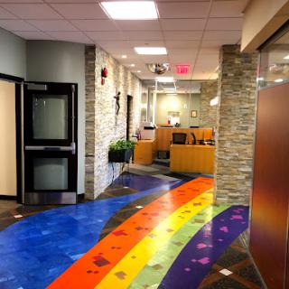 A vibrant hallway featuring a rainbow-colored floor and modern stone walls.