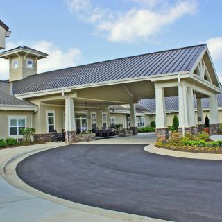 A modern building entrance with a covered driveway and landscaped surroundings.