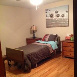 A cozy bedroom with a single bed, wooden furniture, and a decorative painting on the wall.