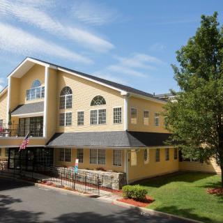 A residential building with a sloped roof and landscaped surroundings.