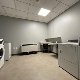 A minimalist laundry room with a washing machine and dryer against gray walls.