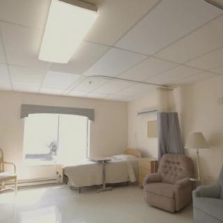 A hospital room with a bed, chair, and window.