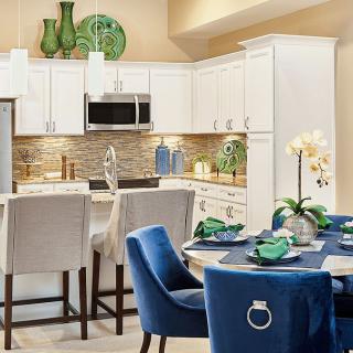 A modern kitchen and dining area with white cabinets, blue chairs, and decorative elements.