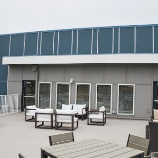 A modern outdoor patio area with seating arrangements and a sleek building facade.