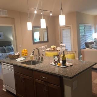 A modern kitchen with an island, featuring pendant lighting and an open floor plan.