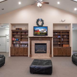 A cozy living room featuring a central fireplace, built-in bookshelves, and a mounted television.