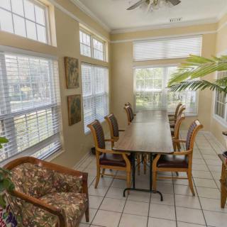 A bright meeting room with a long table and chairs, surrounded by large windows allowing natural light.