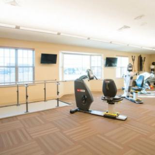 A well-lit fitness center equipped with various exercise machines and rehab tools.