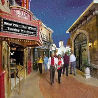 A lively evening scene featuring a group of people walking past a theater marquee in a vibrant shopping area.