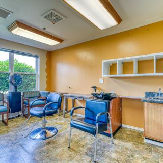 An empty hair salon with chairs, sinks, and bright lighting.
