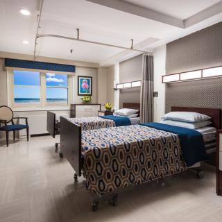 A well-organized hospital room with two patient beds and a view of the ocean.