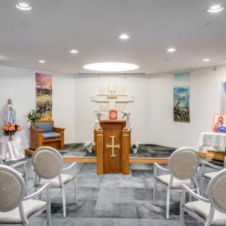 A serene chapel setting featuring an altar, seating for visitors, and religious artwork.