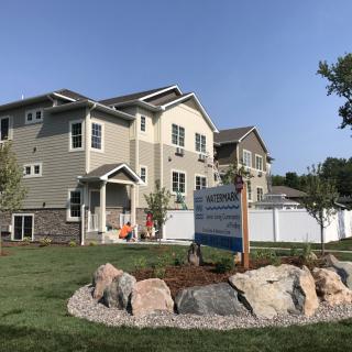 A suburban residential building with a well-maintained lawn and a real estate sign in front.