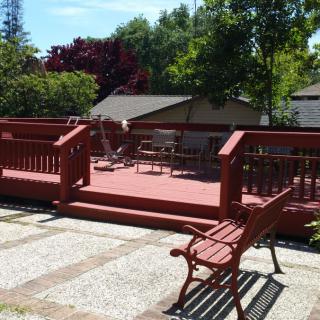 A sunny outdoor deck area with benches and trees in the background.