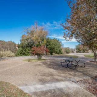 A serene park setting with a picnic table surrounded by autumn foliage under a clear blue sky.
