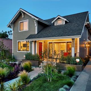 A beautifully lit residential house with a well-maintained garden during the evening.